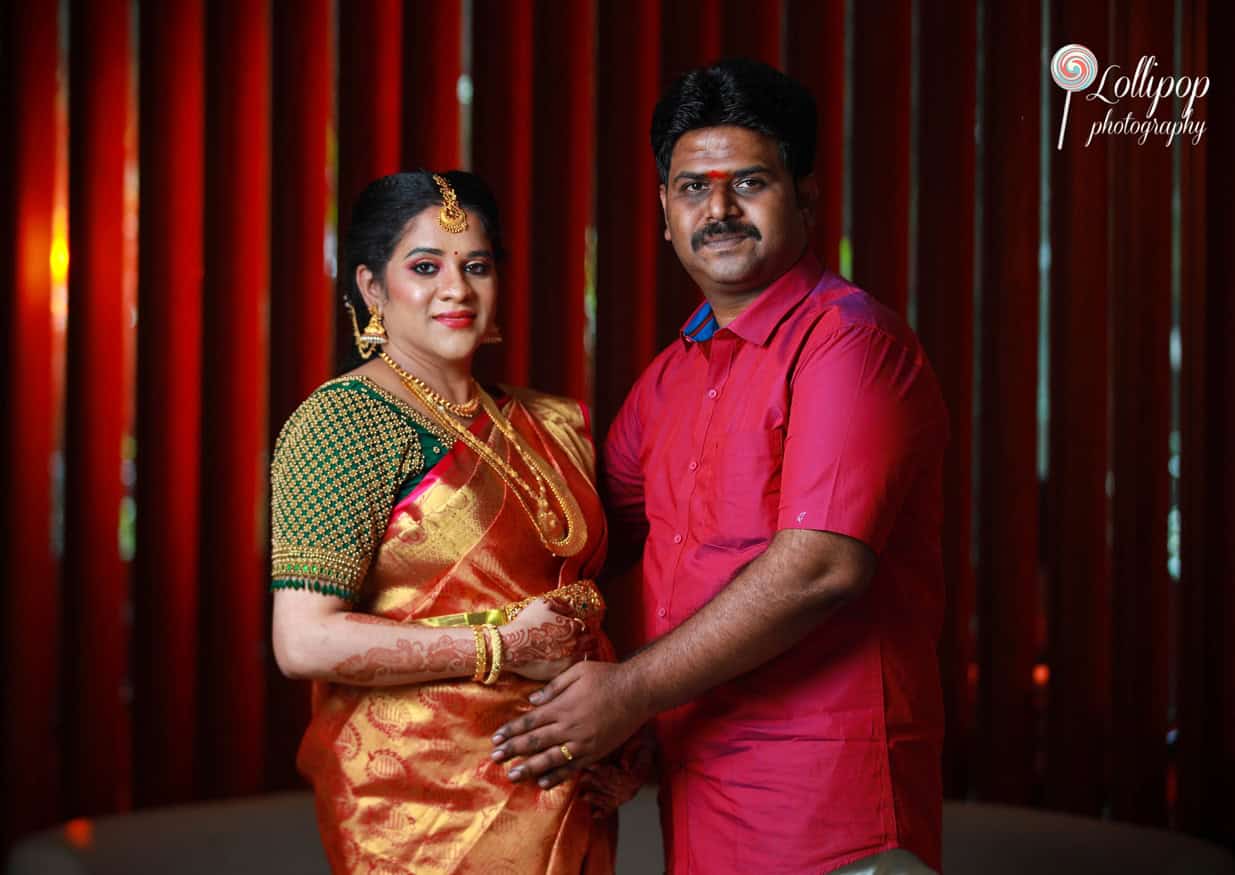 Elegant expectant mother in a traditional saree adorned with gold jewelry at a baby shower in Coimbatore, posing solo with a serene smile.