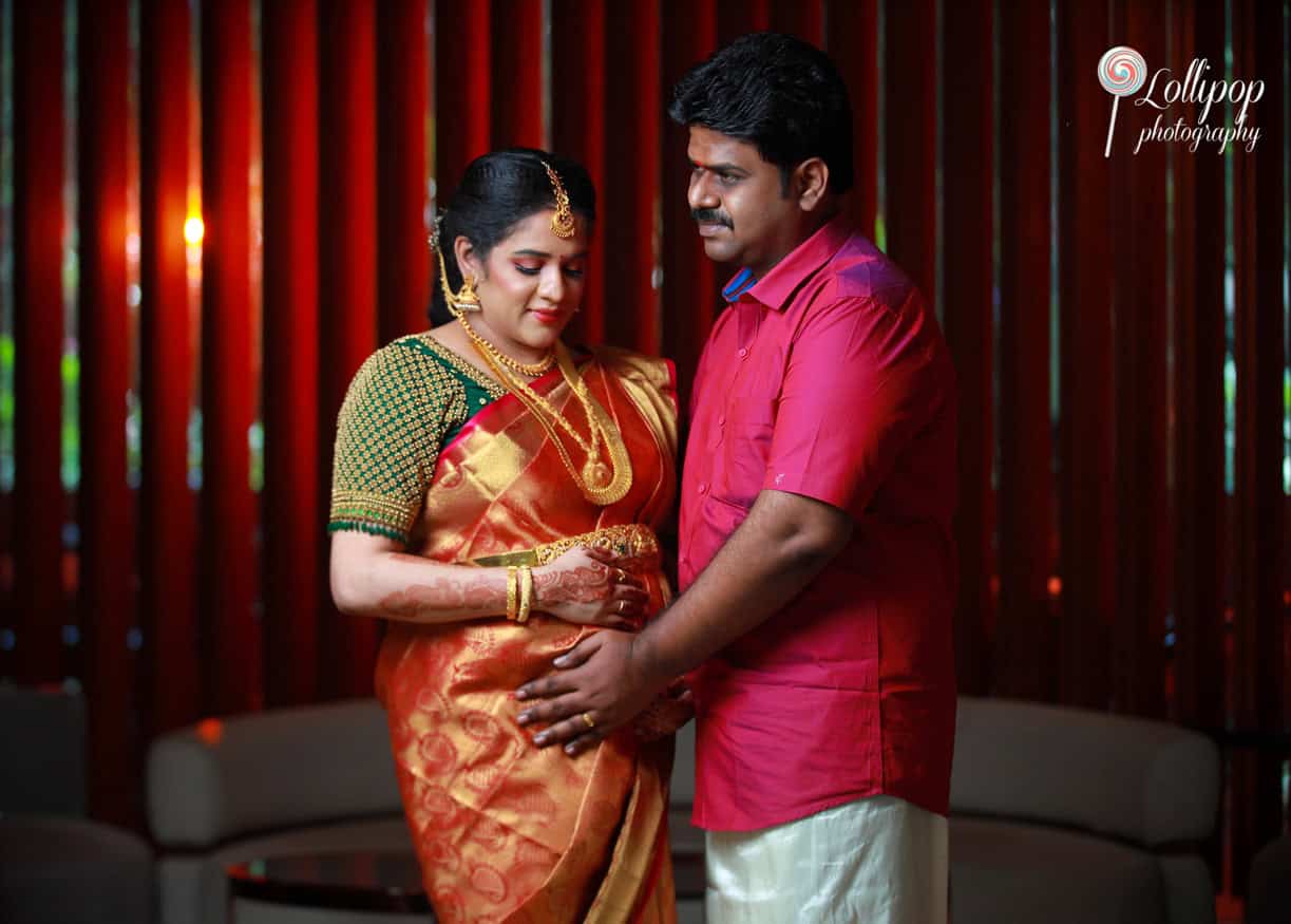 A beautiful capture of a couple dressed in traditional attire at their baby shower ceremony in Coimbatore, with the expectant mother cradling her belly.