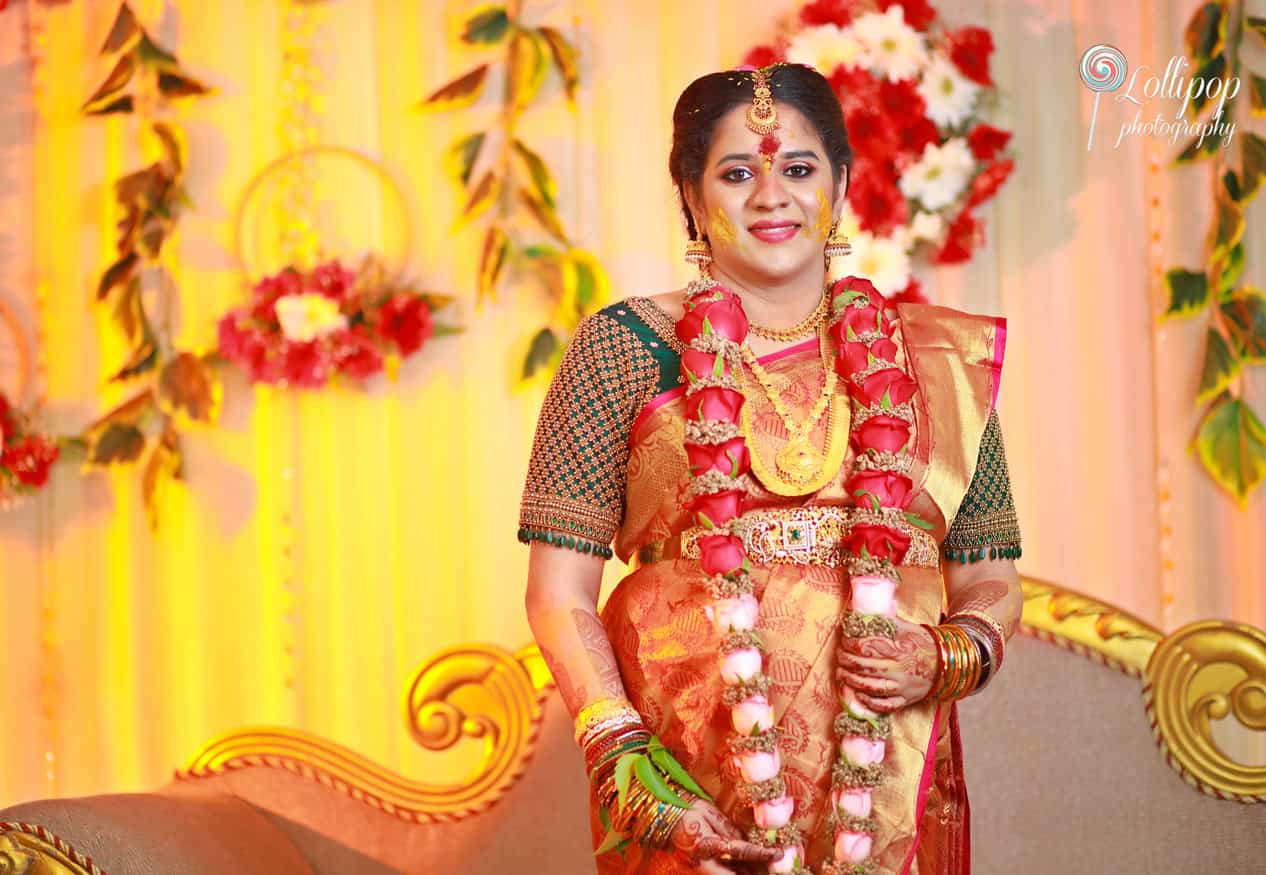 Maternity photo session in Chennai featuring a radiant mother-to-be in a golden traditional saree, decorated with flowers.