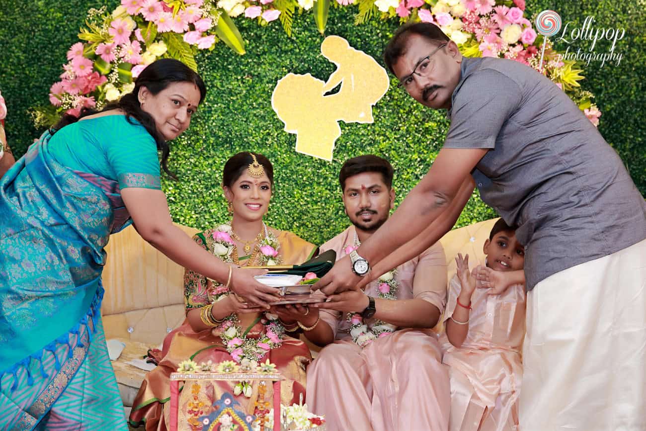 A heartwarming scene from a baby shower with family members offering blessings to the expectant couple, captured with a backdrop of vibrant flowers and greenery in Chennai.