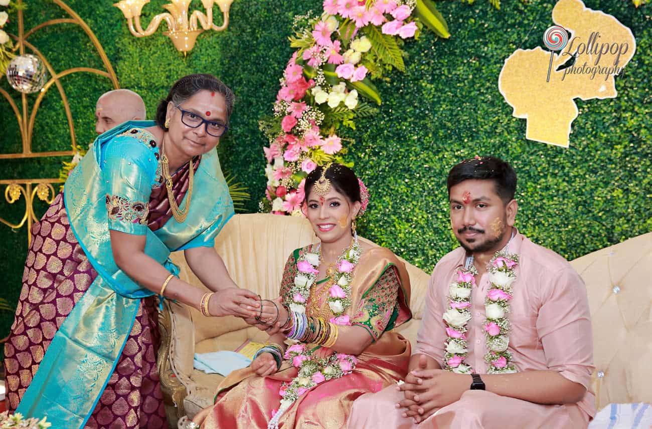 A touching moment as a family gently blesses the expectant couple, seated against a floral backdrop during their baby shower celebration in Chennai.