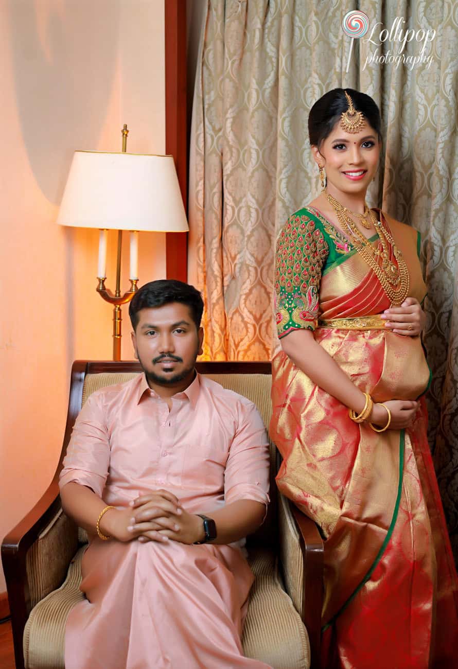 A serene portrait of a pregnant woman in traditional attire seated next to her husband in a calm and cozy indoor setting, part of a baby shower photo session in Chennai.