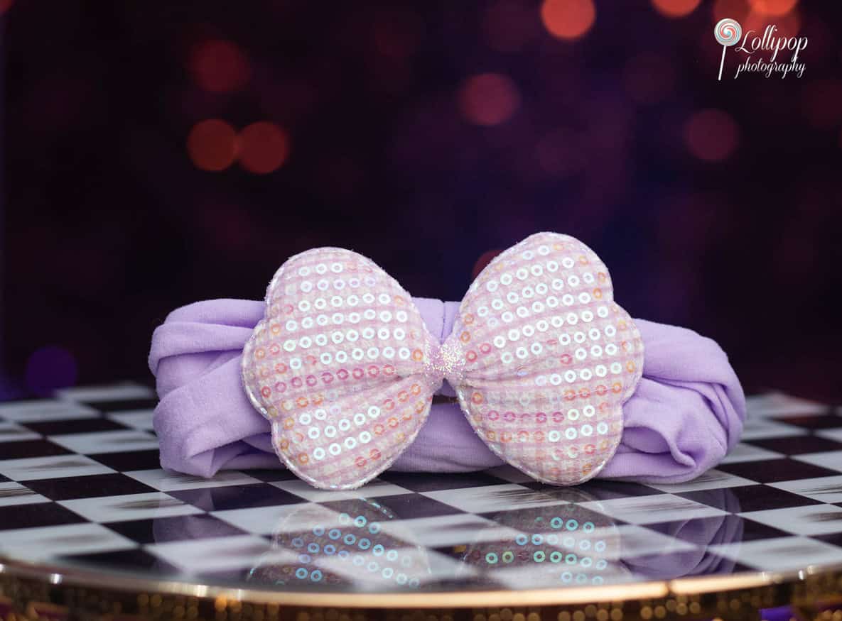 Elegant lavender headband with a large sparkling bow, set against a vibrant bokeh background, capturing the festive spirit of a birthday celebration