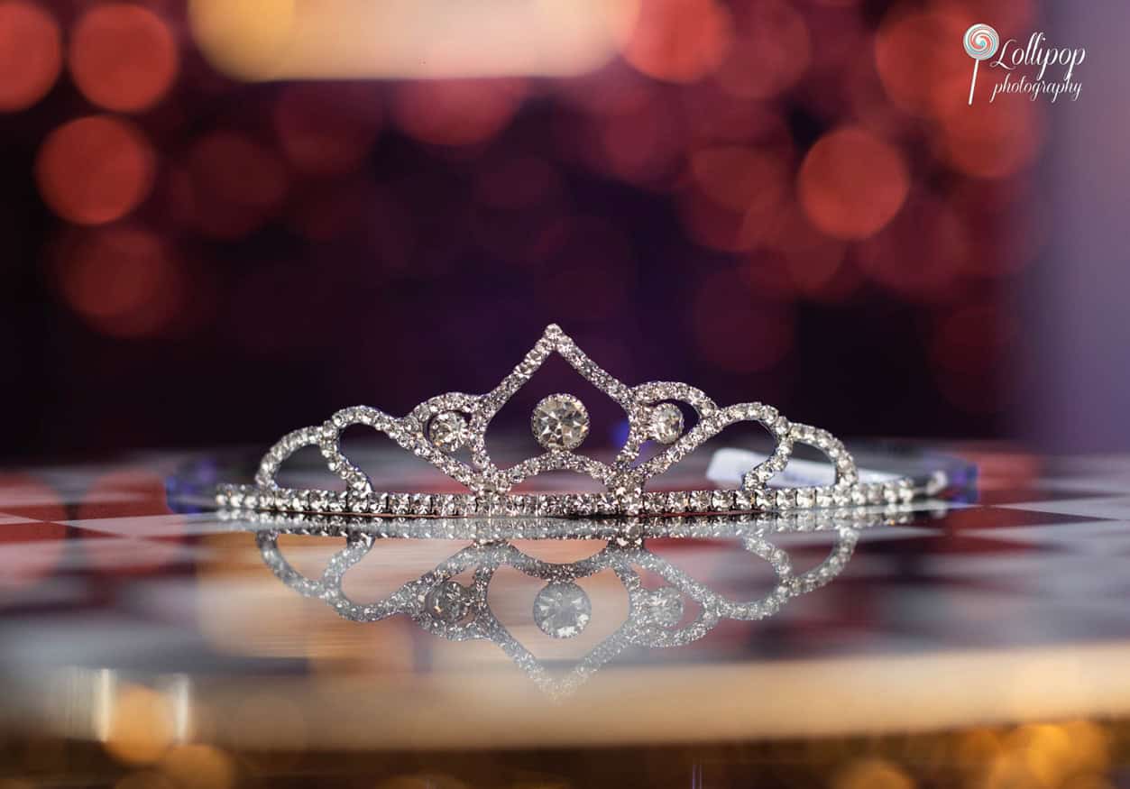 Sparkling tiara resting on a mirrored surface, reflecting the lights of a birthday party, symbolizing a day of royal treatment.