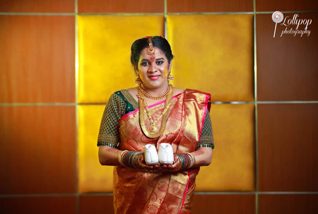 Expectant mother holding baby shoes, a poignant portrait by Lollipop Photography, symbolizing new beginnings.