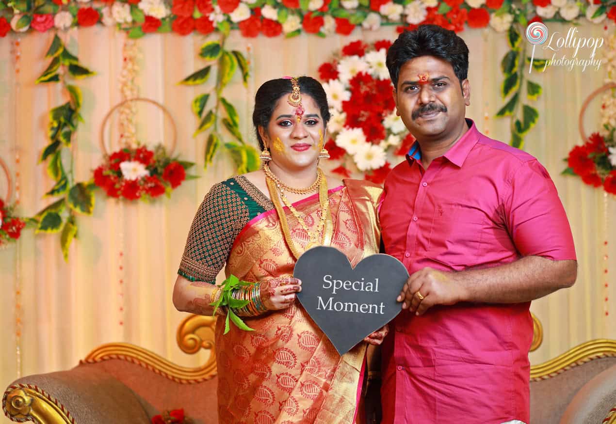 Expectant couple with a 'Coming Soon' sign at their baby shower, a tender moment captured by Lollipop Photography