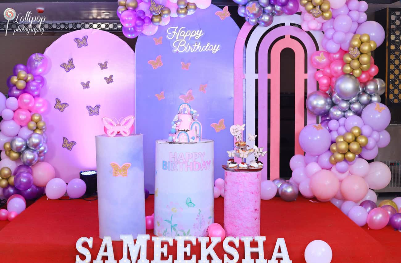 An enchanting birthday event setup featuring a custom cake, colorful balloons, and butterfly decorations, ready for a magical celebration in Chennai by Lollipop Photography