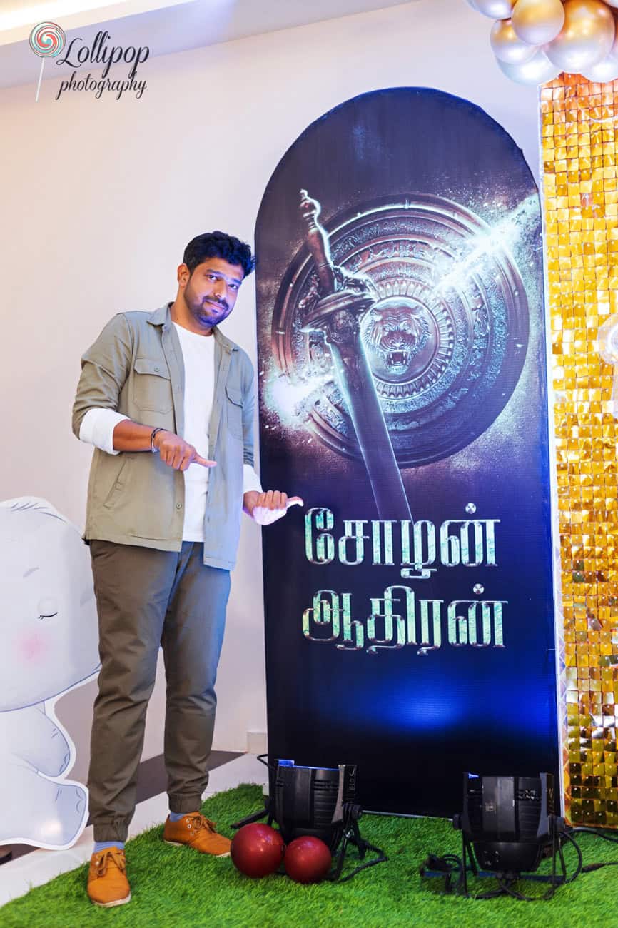 Father poses with a smile by a dramatic movie-themed name board at a birthday party, adding a unique touch to the event, captured by Lollipop Photography in Chennai.