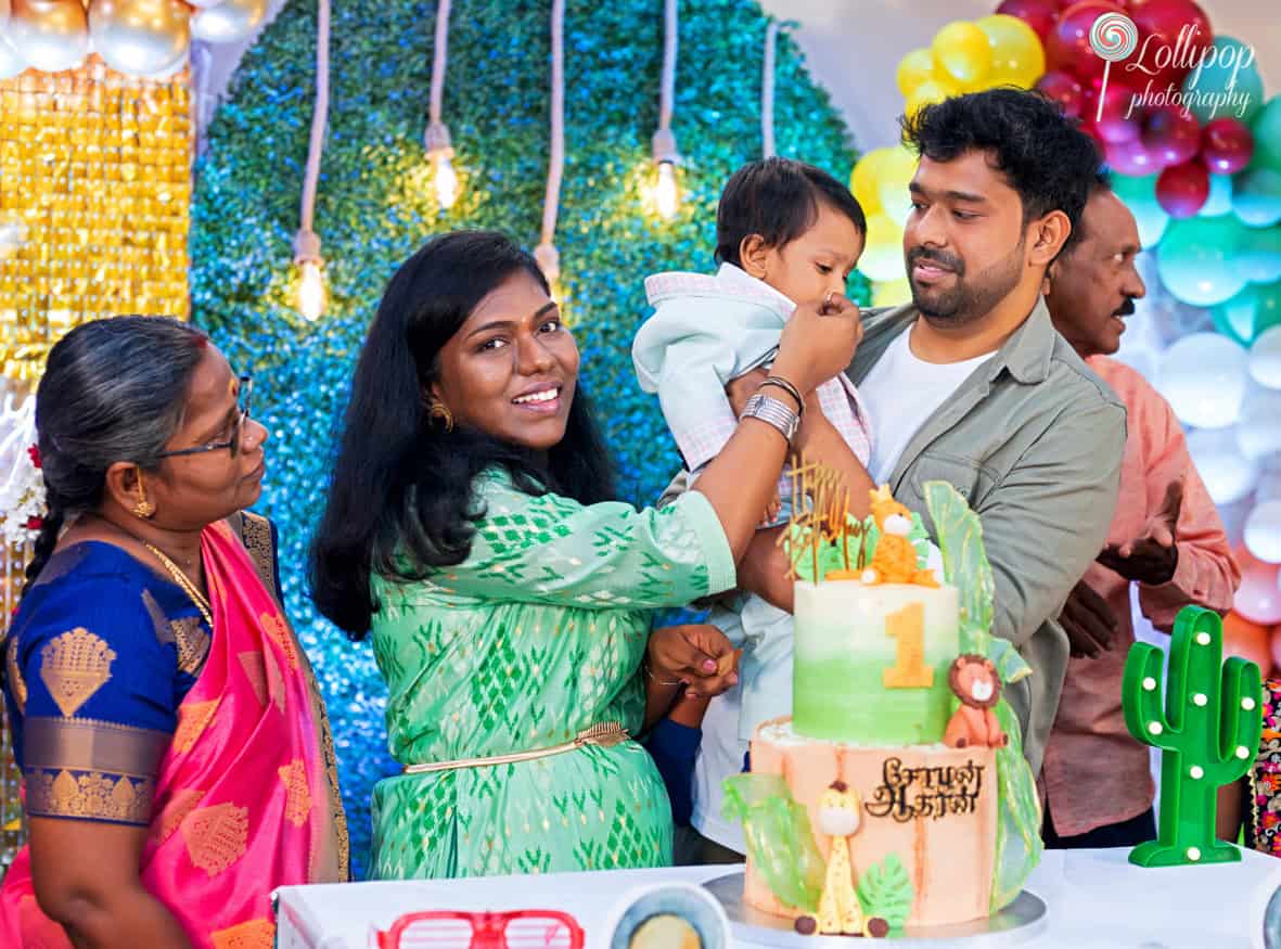 Intimate family gathering around a jungle-themed first birthday cake, featuring joyful expressions, captured by Lollipop Photography in Chennai