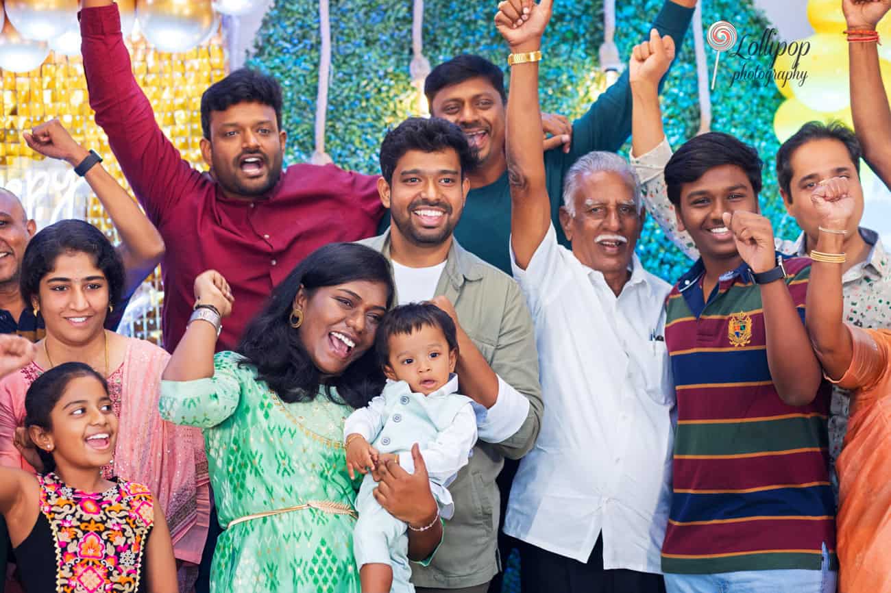 Exuberant large family celebration at a first birthday party with colorful decorations, photographed by Lollipop Photography in Chennai