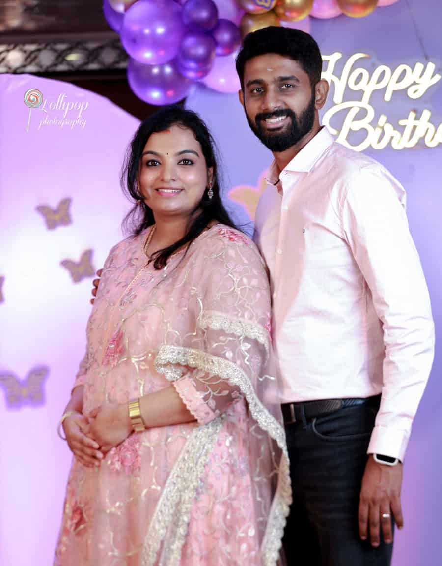 A loving couple shares a gentle moment at their child's birthday celebration, set against a butterfly-themed backdrop by Lollipop Photography in Chennai.