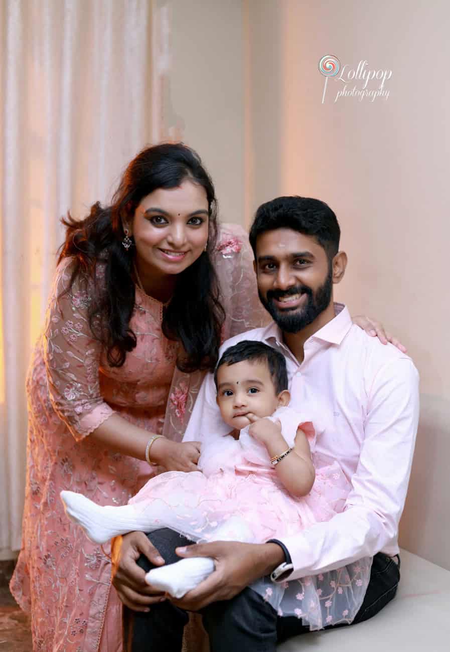 A cozy indoor moment with a young couple and their baby girl, showcasing a close and affectionate family portrait by Lollipop Photography in Chennai.