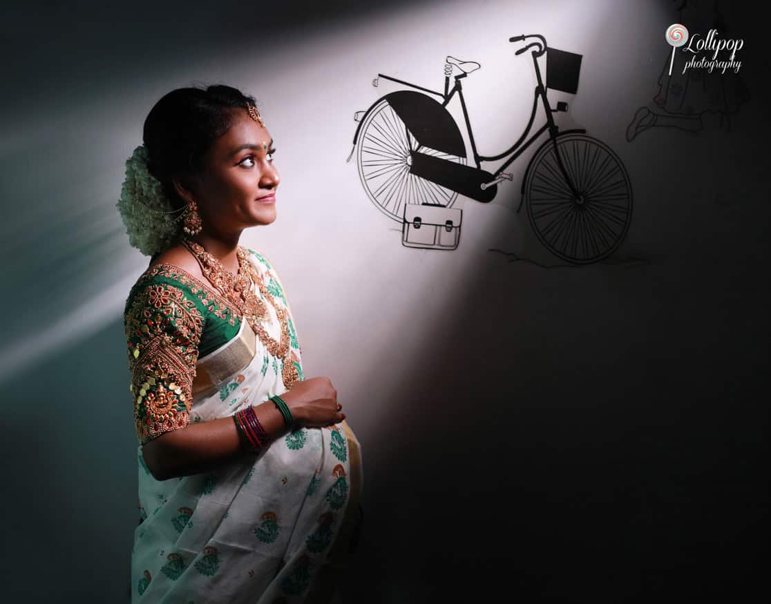 Creative maternity photo capturing a pregnant woman's profile with a playful shadow of a bicycle on the wall, showcasing artistic lighting and composition in Coimbatore.