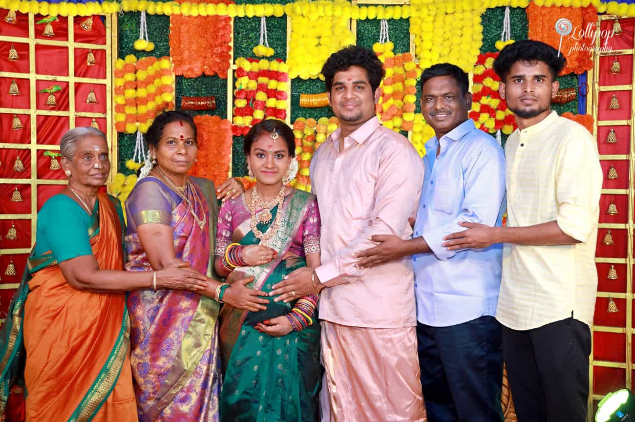 Joyful family maternity celebration featuring a pregnant woman and her family with colorful floral decorations and traditional attire in Coimbatore