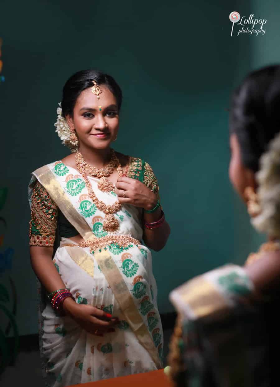 Serene maternity photoshoot featuring a reflective moment of an expectant mother in traditional attire, standing against a dark green background in Coimbatore.