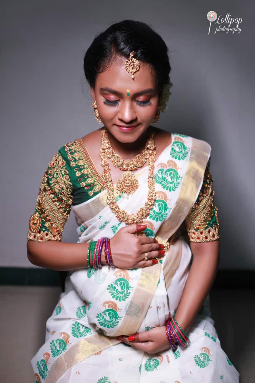 Thoughtful maternity portrait of an expectant mother in traditional South Indian attire, holding her belly gently, captured in Coimbatore