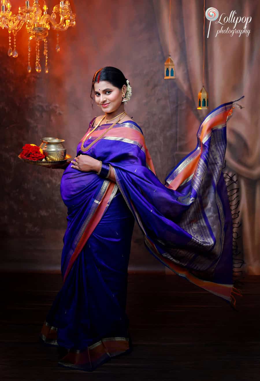 Pregnant woman in a blue sari showcasing her bump, with a stunning silk fabric in a traditional maternity photoshoot in Coimbatore.