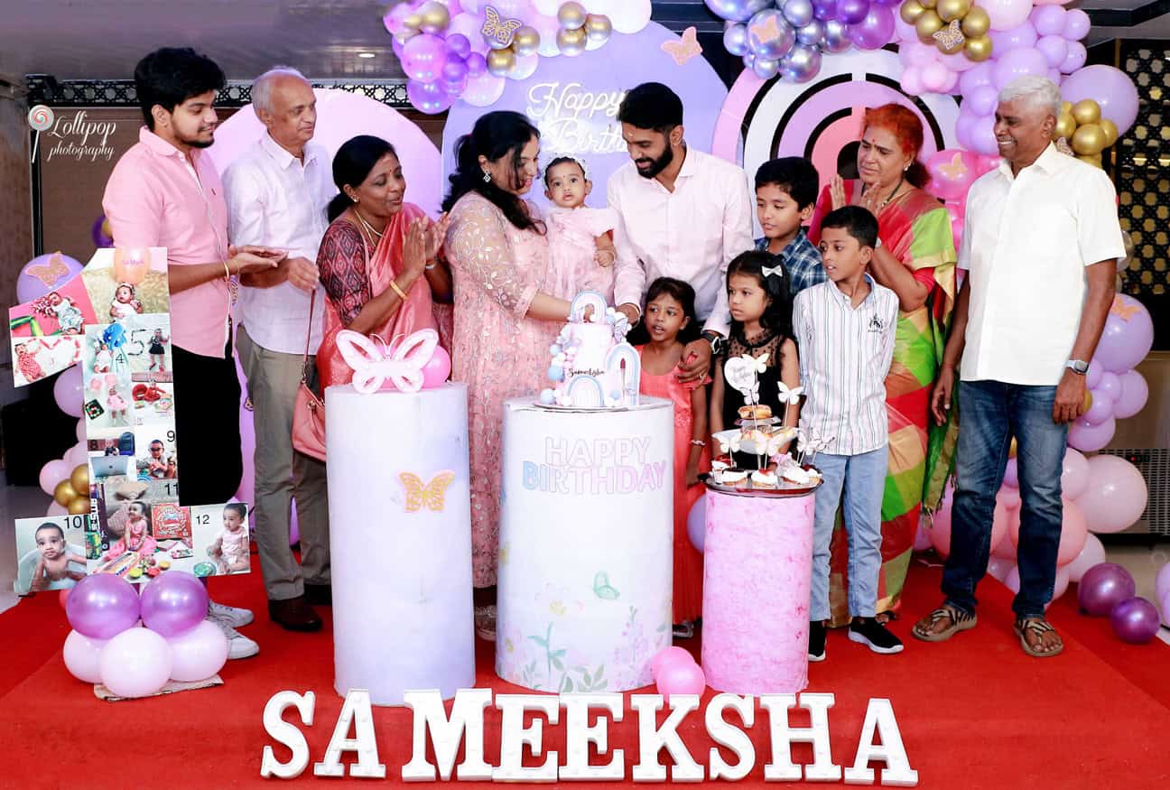 Extended family gathered around a birthday cake at a child's birthday party, with colorful balloons and decorations, captured by Lollipop Photography in Chennai.