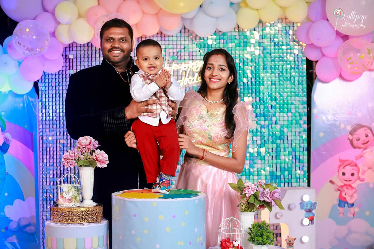 Family celebrating their child's birthday with a cartoon-themed backdrop, featuring colorful decorations and joyful expressions, photographed by Lollipop Photography in Chennai.