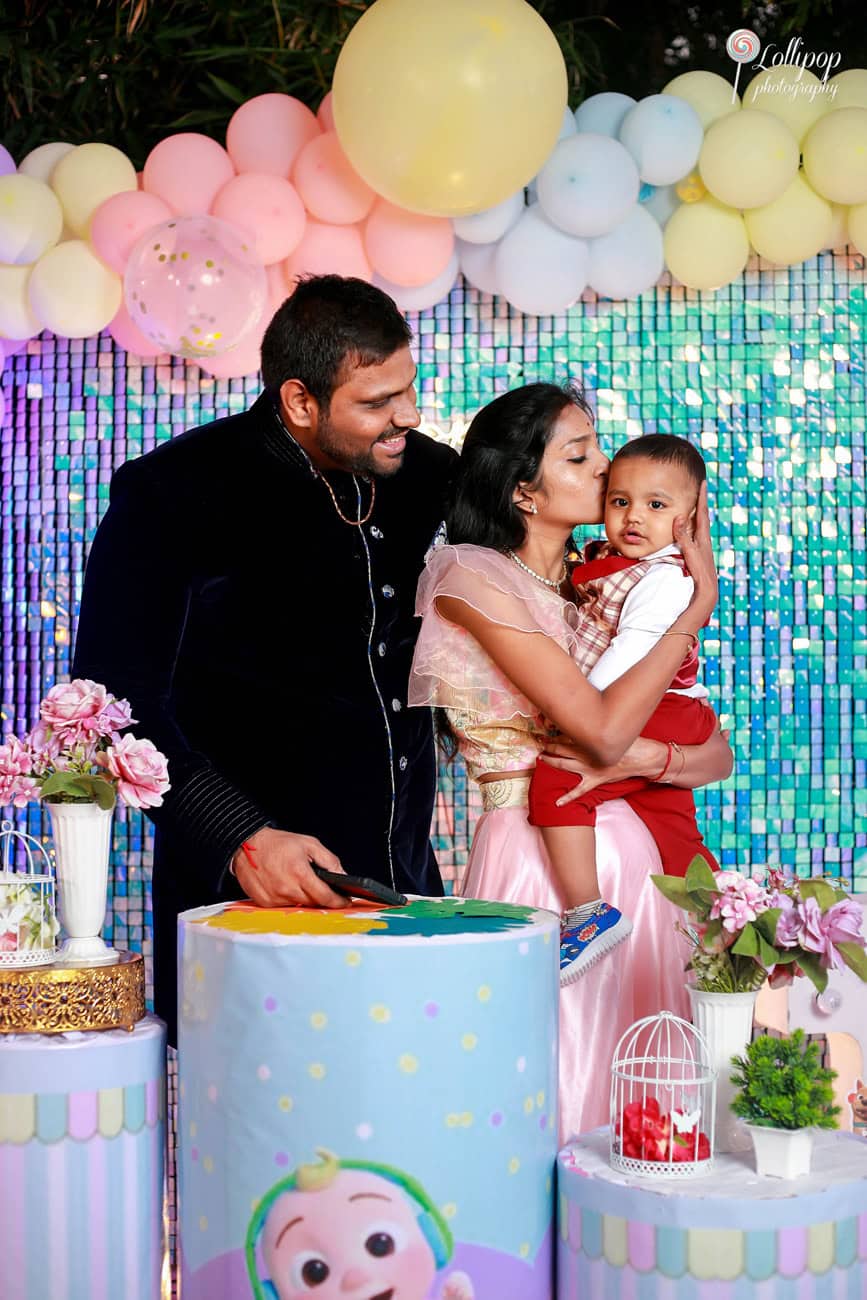 Parents giving their toddler a kiss during his birthday party in Chennai, a tender family moment against a festive background, captured by Lollipop Photography