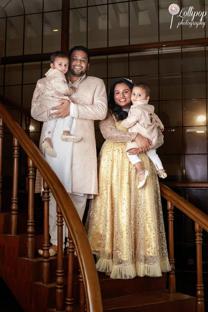 Family of four posing on a grand staircase, all in coordinated traditional attire, during a birthday party in Chennai.