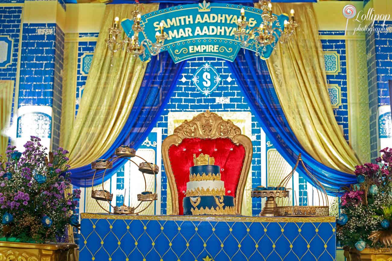 A majestic birthday throne set against a blue and gold backdrop with an elaborate birthday cake, creating a regal setting for a celebration in Chennai