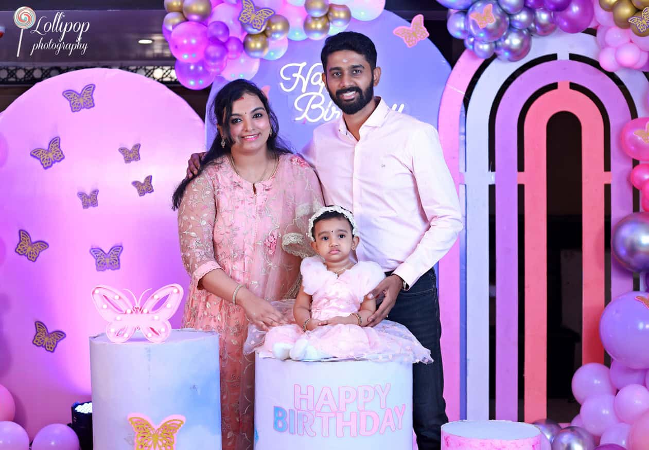 Family portrait at a baby girl's butterfly-themed birthday party, with parents lovingly standing beside their daughter, enhancing the festive mood, captured by Lollipop Photography