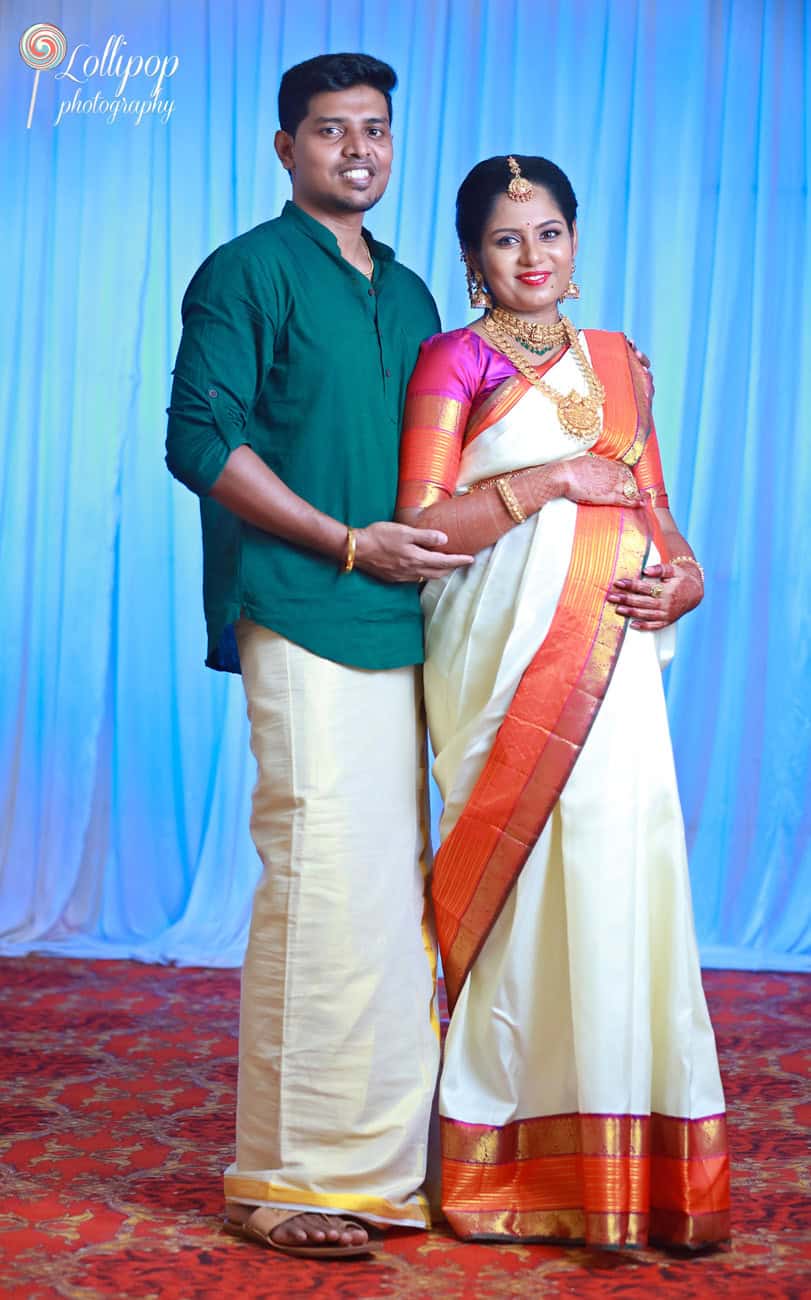 Expectant couple dressed in vibrant traditional wear, sharing a smile in their maternity photo session in Chennai, showcasing their excitement and cultural heritage.