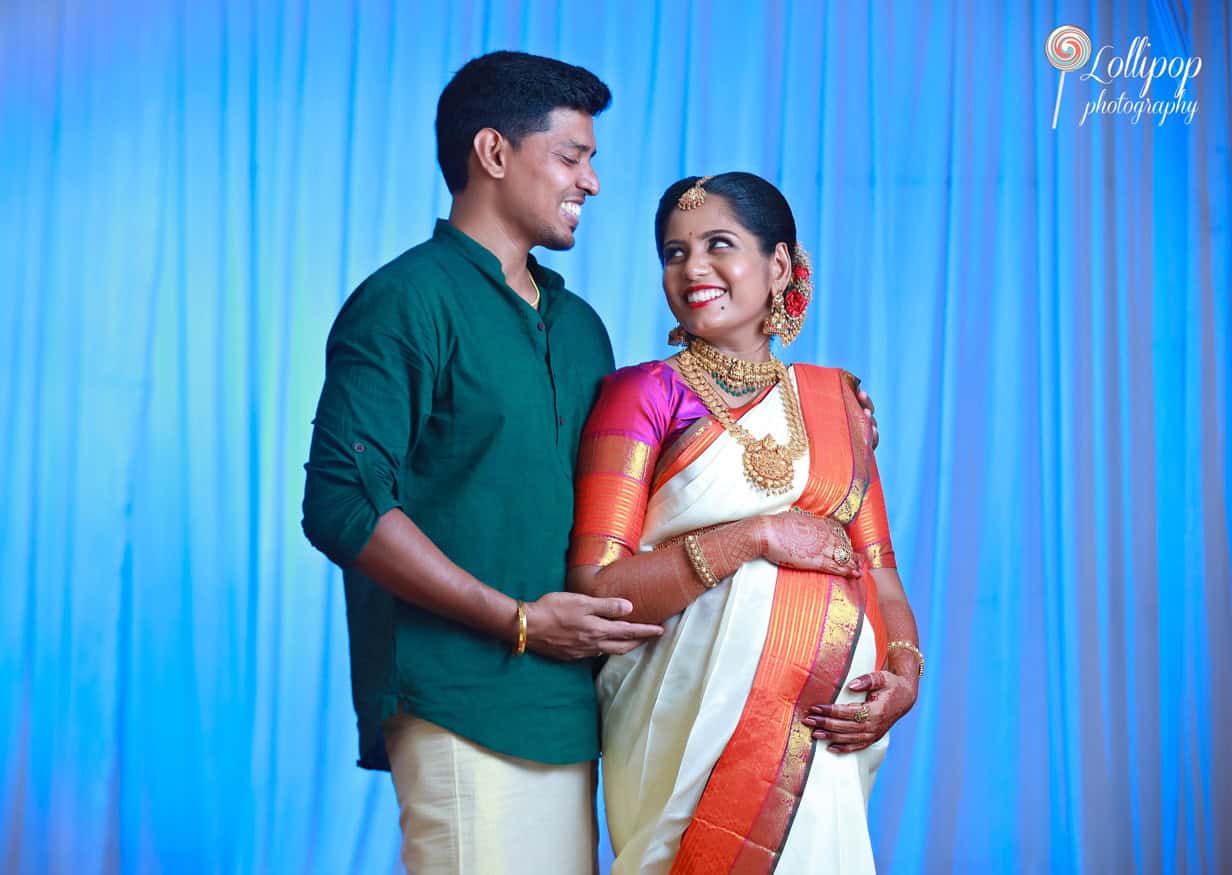 Expectant couple dressed in vibrant traditional wear, sharing a smile in their maternity photo session in Chennai, showcasing their excitement and cultural heritage.