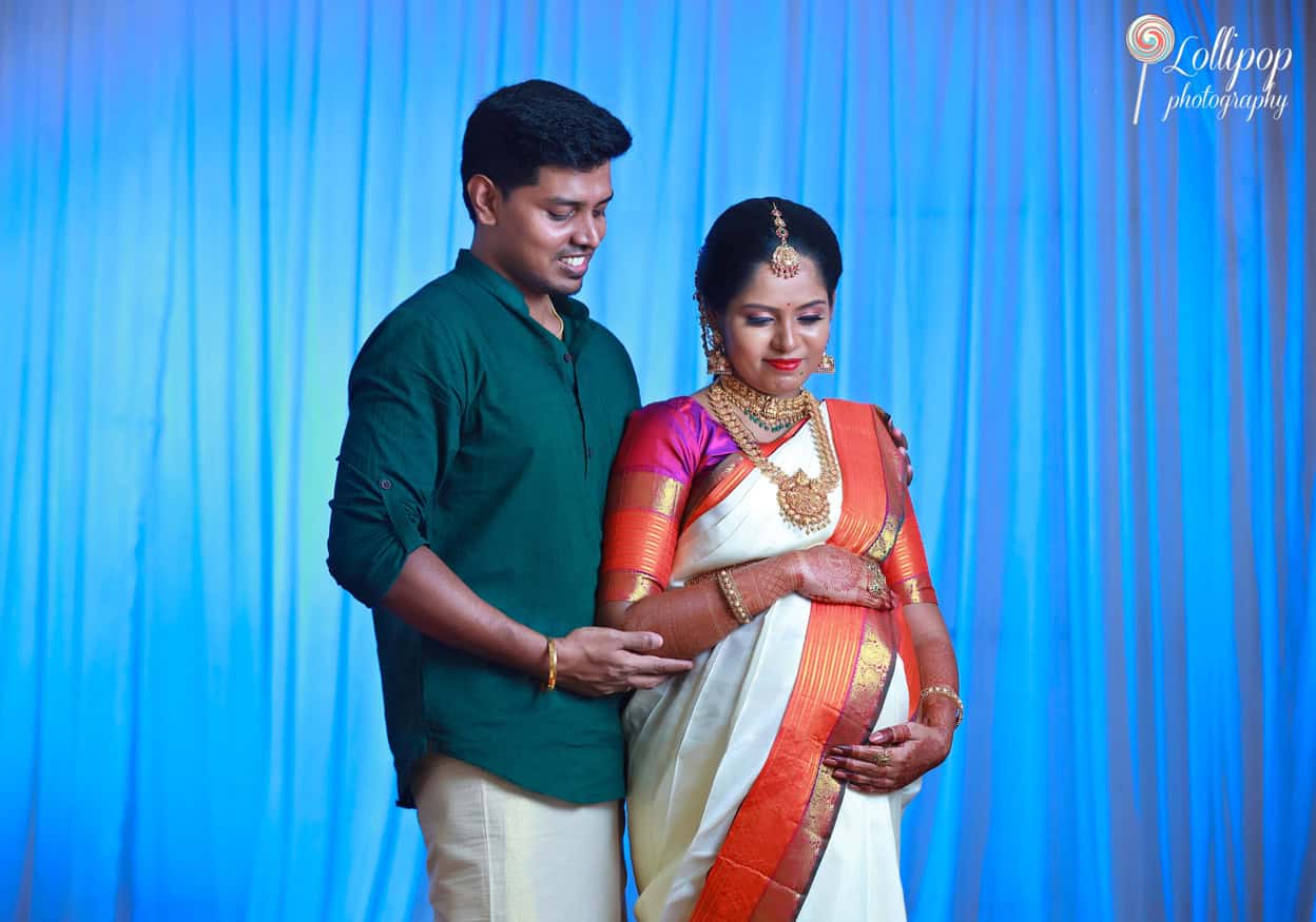 Expectant couple dressed in vibrant traditional wear, sharing a smile in their maternity photo session in Chennai, showcasing their excitement and cultural heritage.