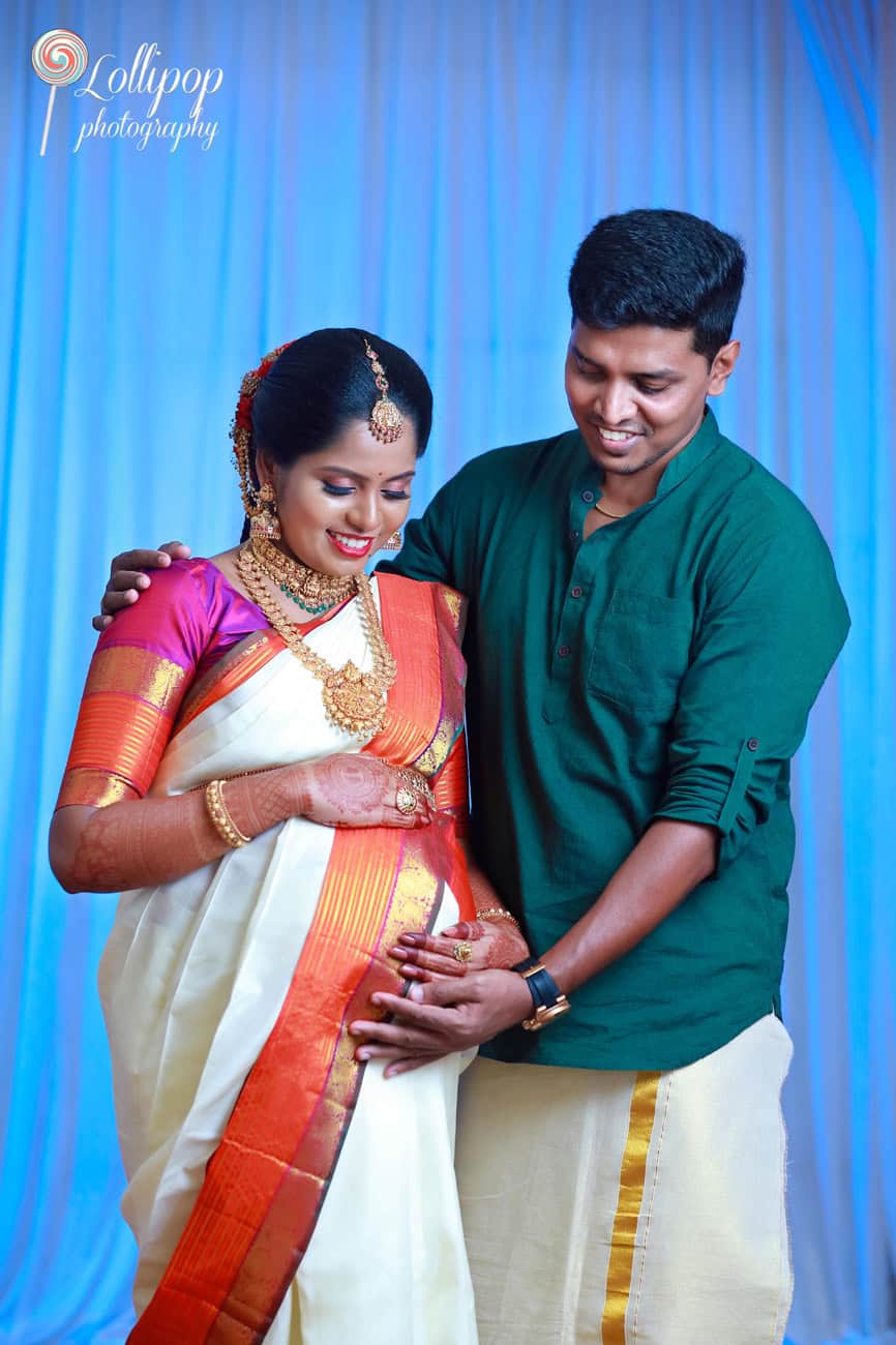 A tender moment captured between a husband and his radiant wife in traditional attire during their maternity photoshoot in chennai, set against a serene blue backdrop.