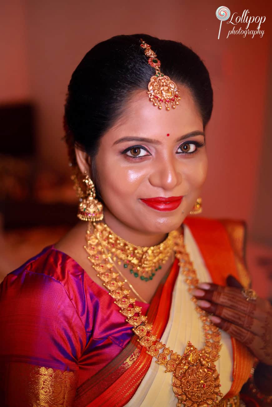 Portrait of a smiling expectant mother in traditional attire and exquisite gold jewelry, radiating happiness at her baby shower in Chennai, captured by Lollipop Photography.