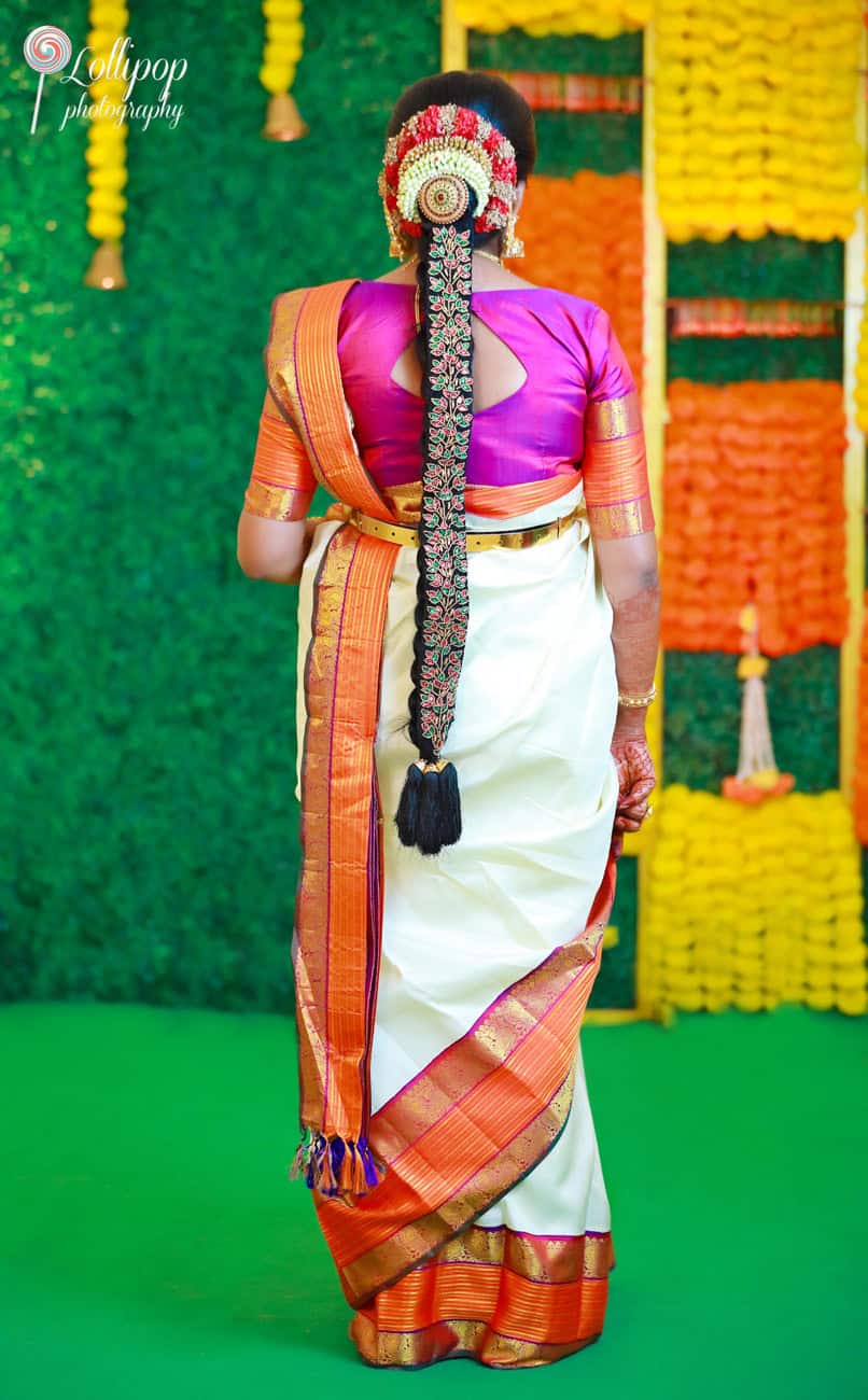 A unique back view of a pregnant woman showcasing traditional South Indian braid and saree, set against a colorful floral wall in Chennai.