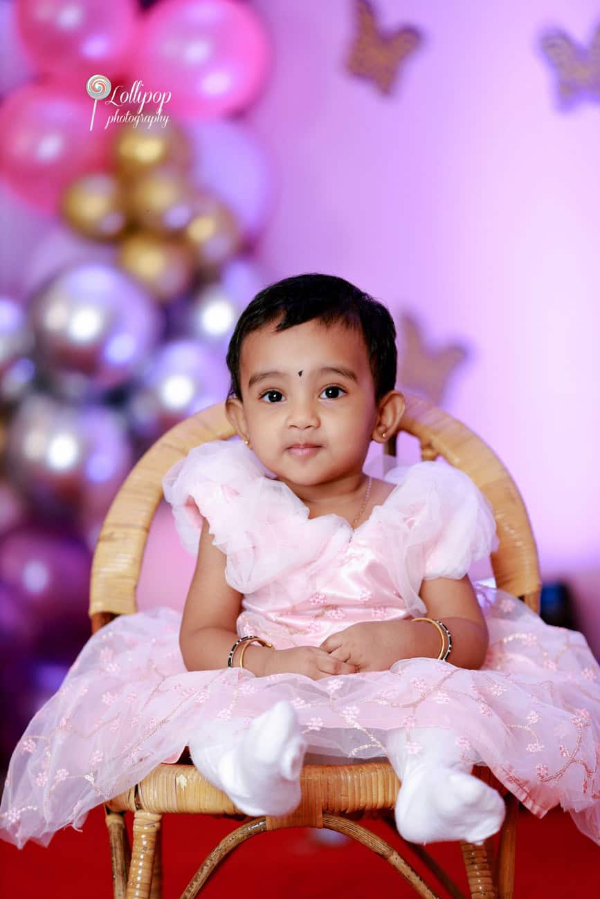 Cheerful toddler boy in school uniform at a studio photoshoot with educational chalkboard backdrop in Chennai.