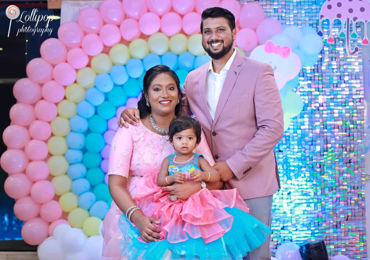 Kanali's family stands proudly at her birthday celebration, framed by a colorful balloon arch, photographed by Lollipop Photography in Chennai