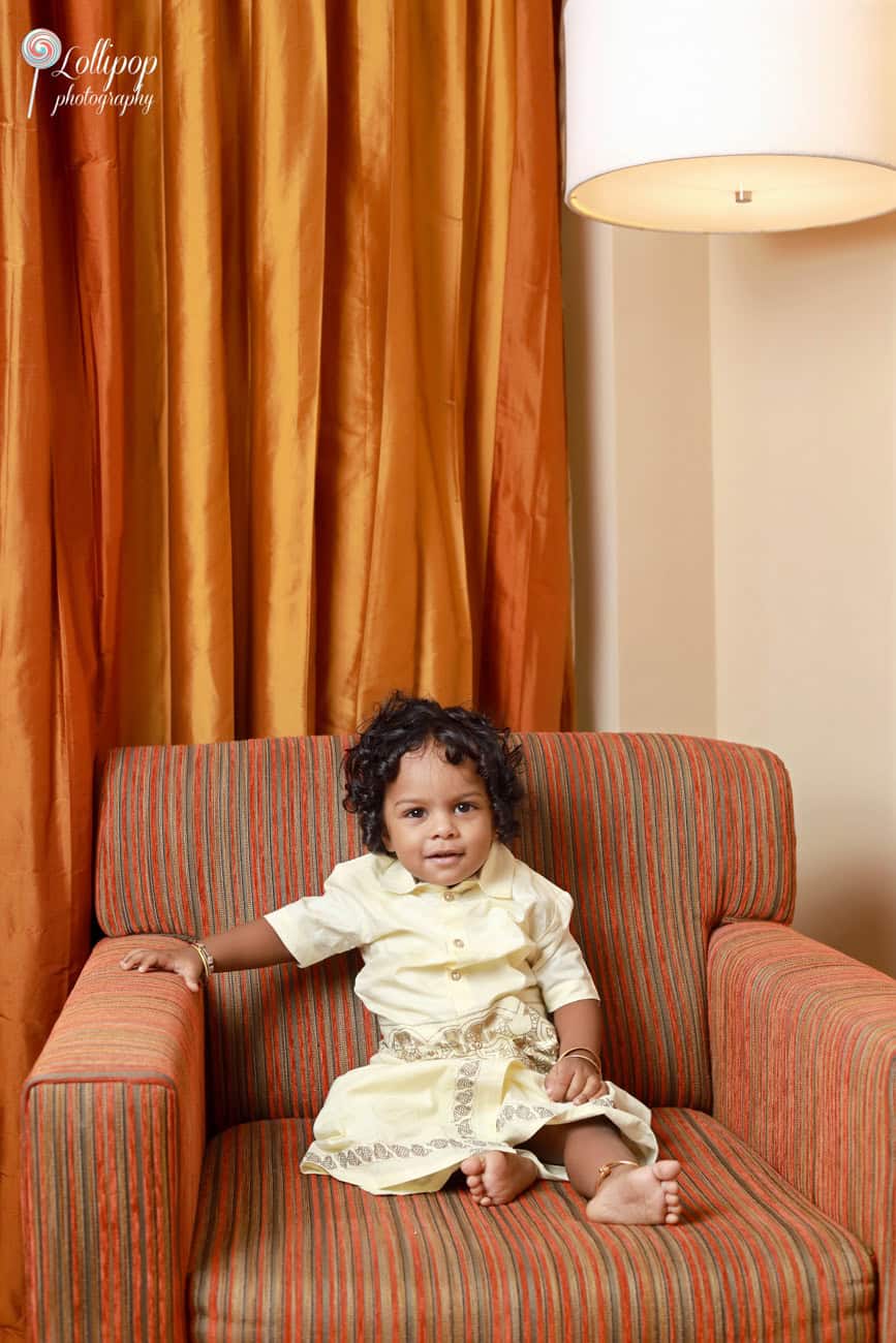 Aryan, seated in an armchair with a big smile, dressed in traditional attire on his birthday in Chennai, photographed by Lollipop Photography