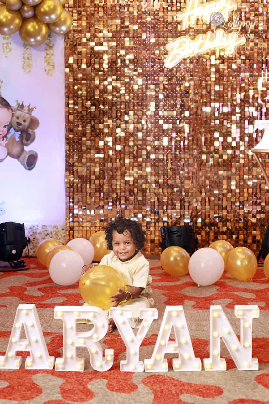 Aryan smiles as he holds a balloon with his name decoratively displayed in lights, captured by Lollipop Photography