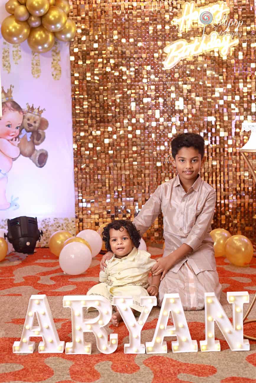 Aryan and his brother share a close moment in front of the shimmering birthday decor, captured by Lollipop Photography