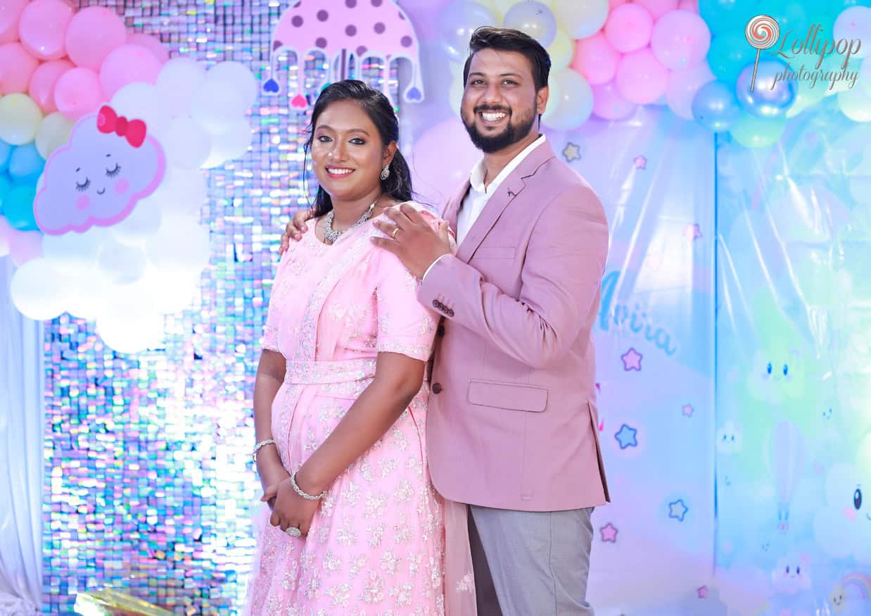 The happy couple smiles together at Kanali's birthday, surrounded by vibrant balloon decor, captured by Lollipop Photography