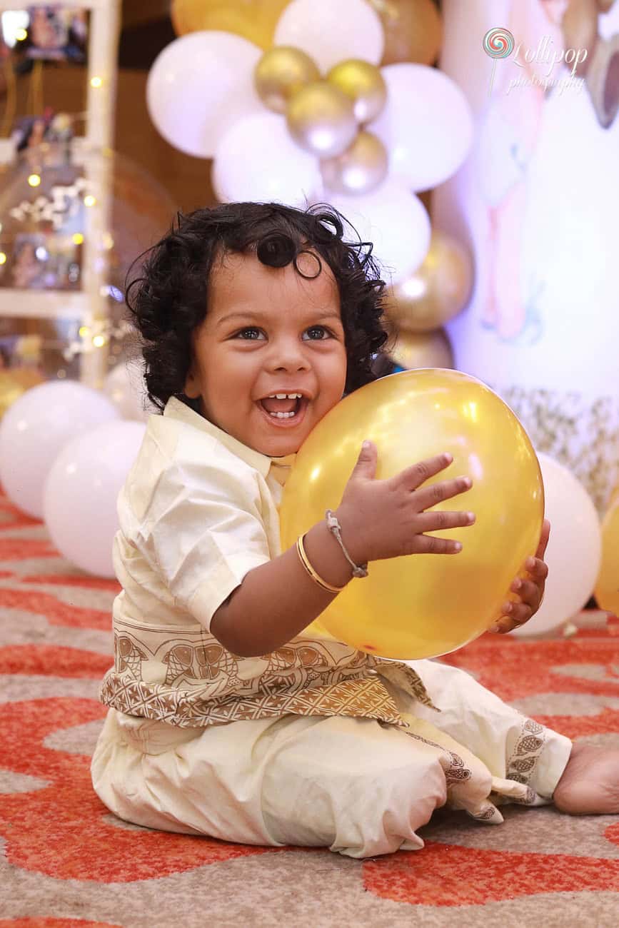 A joyful close-up of Aryan smiling with a golden balloon at his birthday celebration, captured by Lollipop Photography