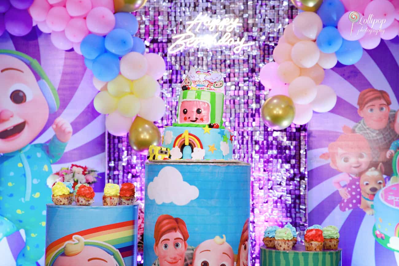 A vibrant birthday cake decorated with balloons and a rainbow theme, perfectly set up for Kian's birthday event in Chennai by Lollipop Photography.