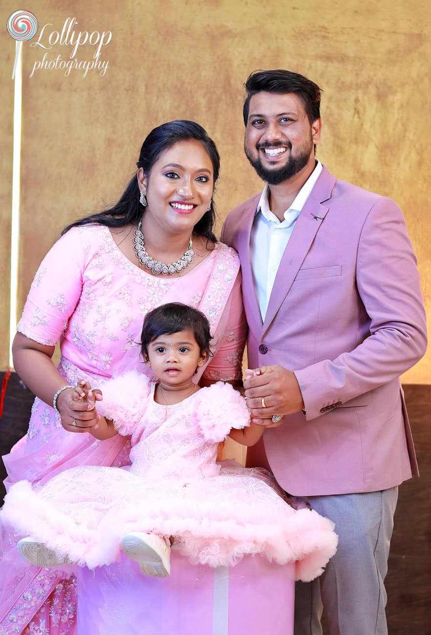 Kanali celebrates her first birthday with her parents in a sweet family portrait, set against a golden backdrop, captured by Lollipop Photography.