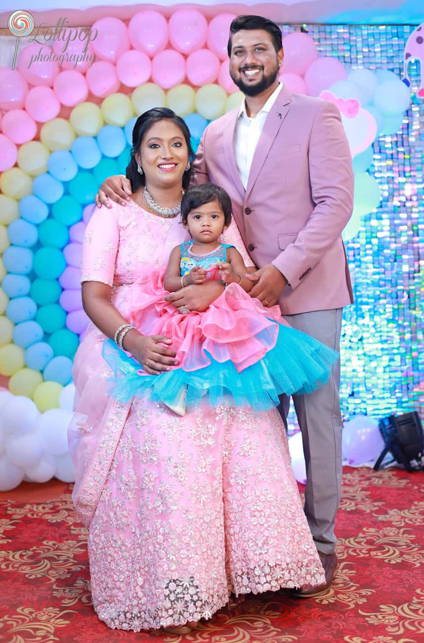 A warm family portrait celebrating Kanali's birthday, with parents and the little one dressed in pastel hues, captured by Lollipop Photography