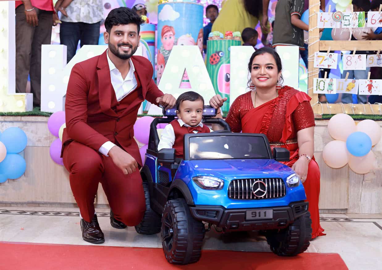 Kian poses with his parents beside his toy car at his birthday celebration in Chennai, beautifully photographed by Lollipop Photography.