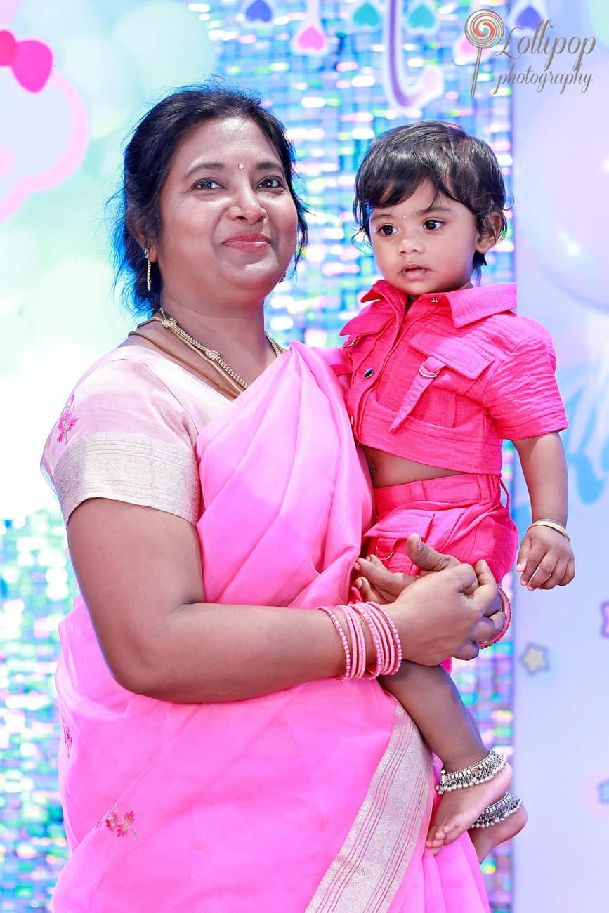 Kanali and her grandmother share a close moment during her birthday celebration, with Kanali dressed in an adorable pink outfit, captured by Lollipop Photography