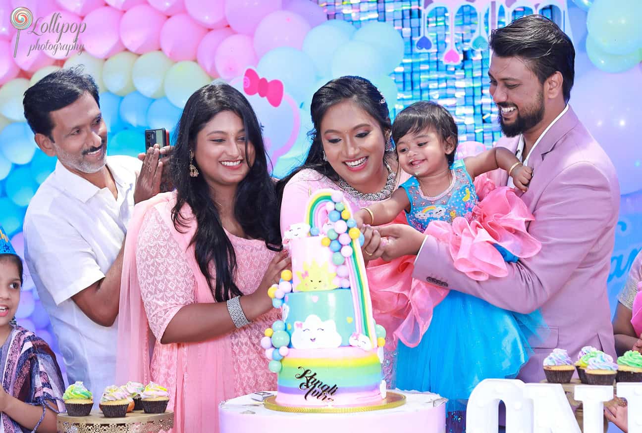 Kanali smiling as her family gathers around for her birthday cake cutting, captured by Lollipop Photography with colorful party decor in the background