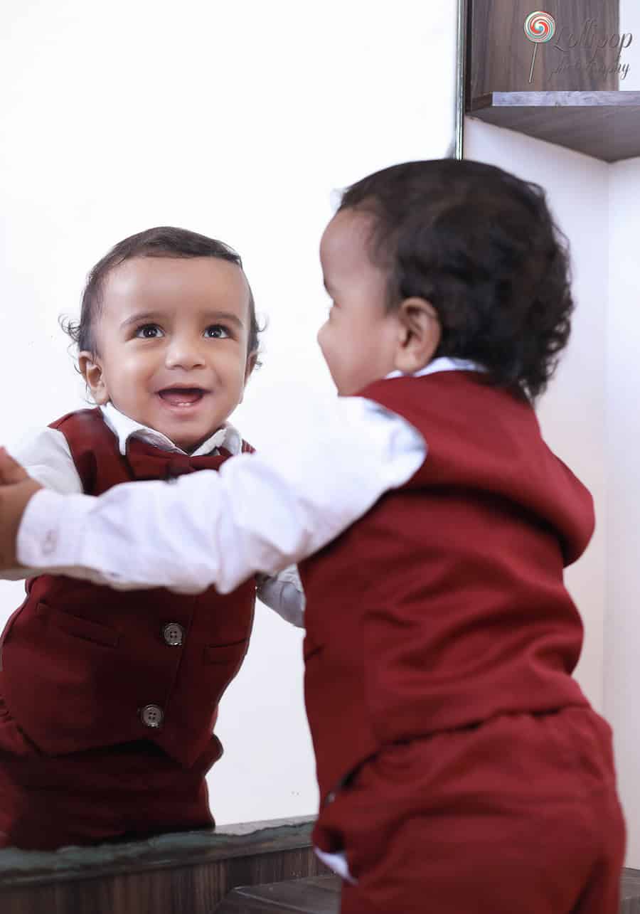 Kian smiling at his reflection in the mirror, capturing a precious moment in his birthday photoshoot by Lollipop Photography in Chennai