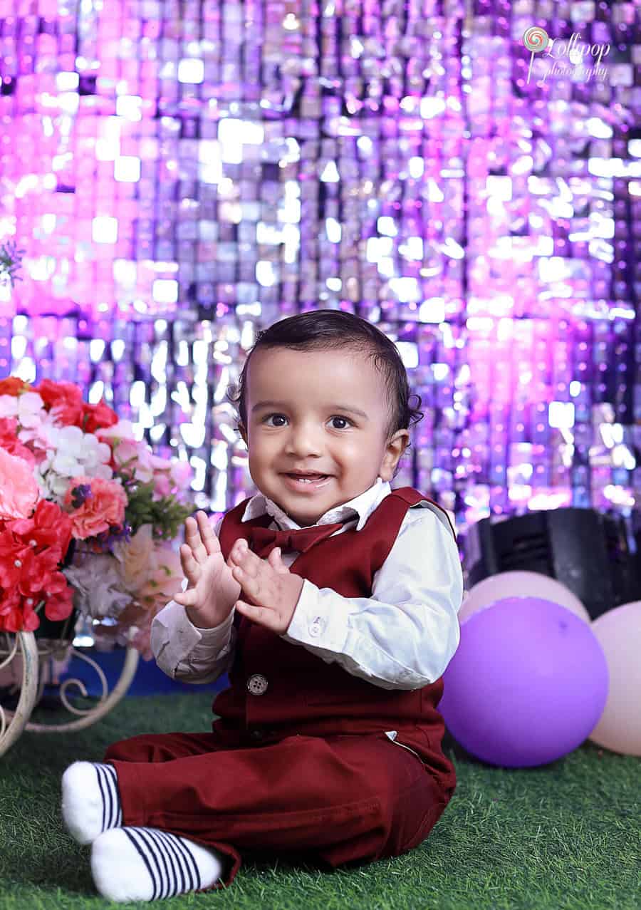 Happy Kian clapping with joy during his first birthday photoshoot in Chennai, captured beautifully by Lollipop Photography.