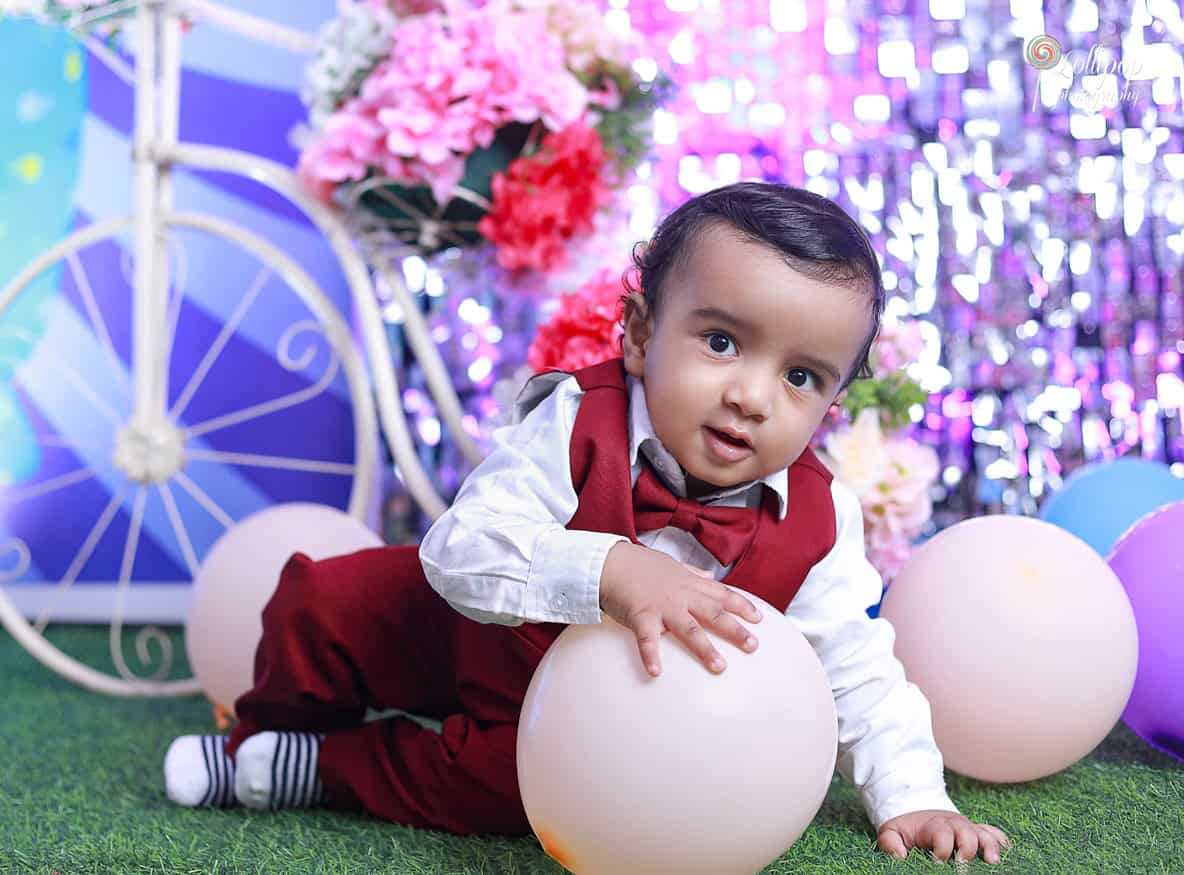 Playful Kian engaging with balloons on the grass, bringing joy to his birthday photoshoot by Lollipop Photography in Chennai.