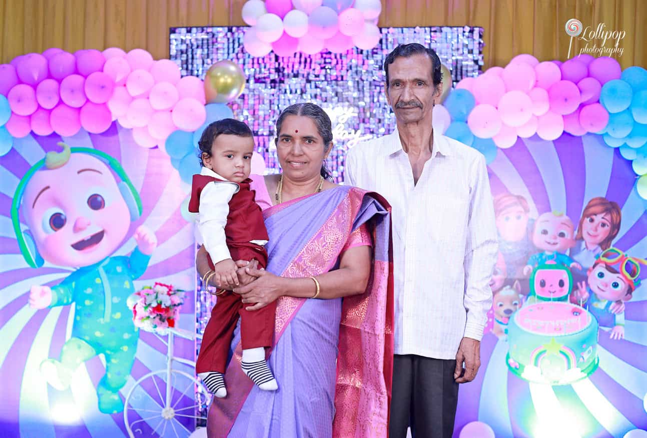 Kian held by his grandparents, surrounded by colorful decor, in a birthday photoshoot by Lollipop Photography in Chennai.